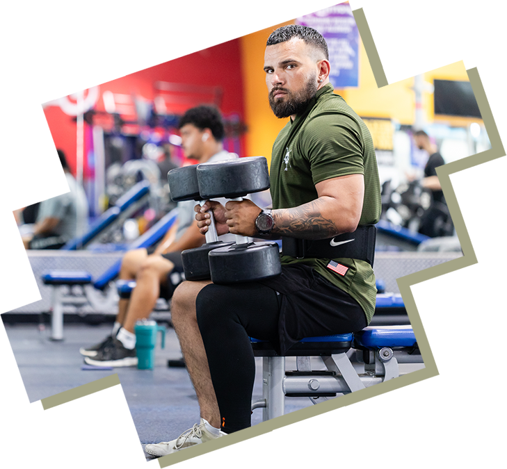 A man is sitting on a bench holding two dumbbells.